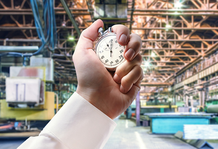 Hand mit Stoppuhr vor Produktionsumgebung